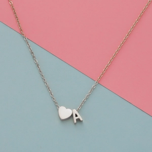 Detailed view of silver heart and letter A charms on a sleek metal necklace