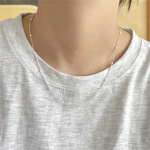 Close-up of minimalist 925 sterling silver chain with white beads on a model neck