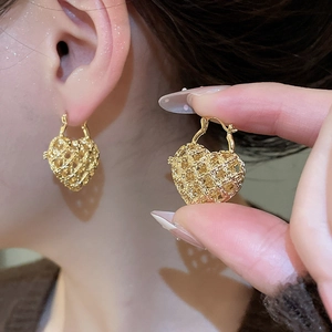 Detail of vintage heart-shaped woven metal earrings with textured gold finish