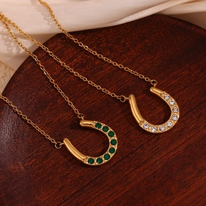 Detail of horseshoe pendants in 18K gold plated steel with green and white crystals