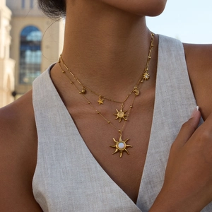 Detail of 18K gold stainless steel layered necklace with opal sun and star pendants