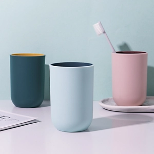 Three minimalist matte plastic mouthwash cups in teal, blue and pink for home bathroom use