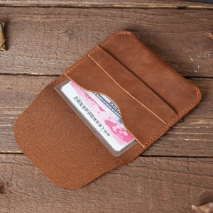 Retro brown crazy horse leather card holder with clear ID window on vintage wood background