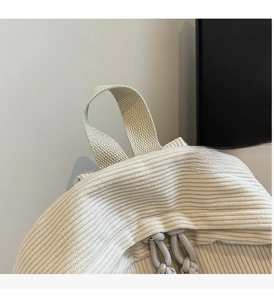 Detail of corduroy backpack showing beige fabric texture and durable top handle