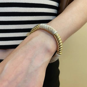 Detailed shot of an elastic twist bracelet with gold metal and cream acrylic textures