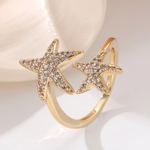 Close-up of golden starfish rings with white cubic zirconia and adjustable open band