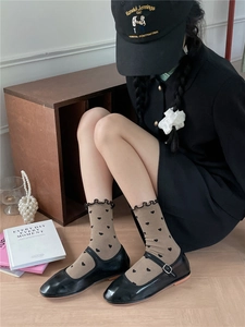 Detail of brown heart-patterned socks with ruffle trim and black Mary Jane shoes