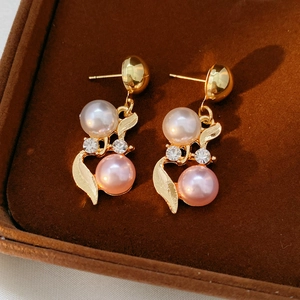 Gros plan de boucles d'oreilles vintage avec perles blanches et roses en boîte velours