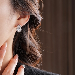Detail of silver gourd stud earring with sparkling zircon crystals on a female model