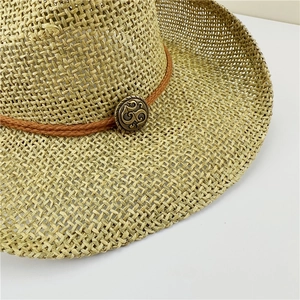 Close-up of hollowed straw jazz hat featuring a vintage bronze buckle and brown rope