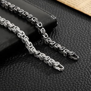 Close-up of vintage stainless steel Byzantine chain with intricate woven links on leather