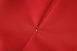 Close-up of invisible back zipper detail on a red strapless dress with smooth stitching