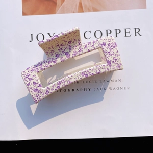 Detail of a large rectangular matte hair claw clip with purple ink splatter patterns