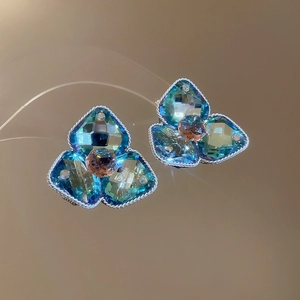 Detail von Blumenohrsteckern mit blauen Kristallen und gedrehtem Metallrand