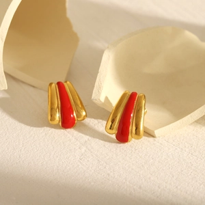 Detailed shot of vintage gold-plated ray earrings with red enamel on textured stone