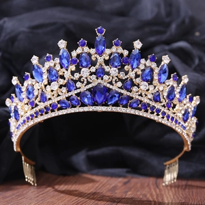 Macro detail of golden baroque crown featuring blue teardrop gems and white rhinestones