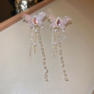 Close-up of pink butterfly earrings with crystal tassels and pearls on beige tray