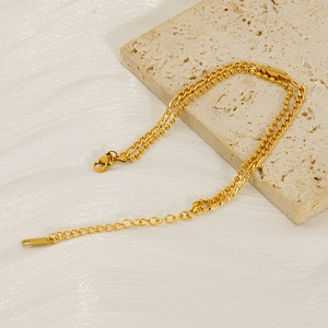 Minimalist double-layered gold stainless steel chain bracelet on a travertine stone base