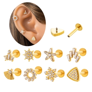 Detailed views of gold titanium piercing studs featuring snowflake and crown crystal designs