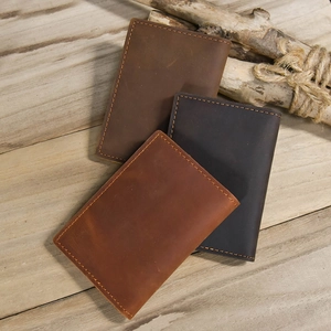 Close-up of three genuine crazy horse leather coin purses with manual stitching on wood