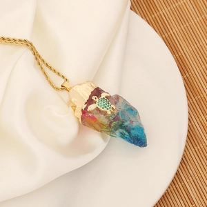 Detail of a natural crystal pendant with a gold turtle accent on white silk fabric