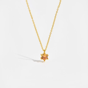 Detail of s925 silver necklace with orange cubic zirconia in a six-prong gold setting