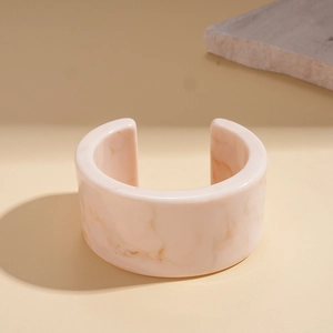 Macro detail of amber marbled resin cuff bracelet featuring a minimalist C-shape design