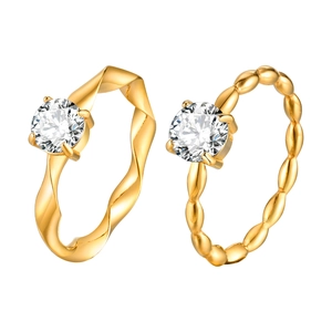 Golden Mobius ring and beaded band with single zircon stones on a white background