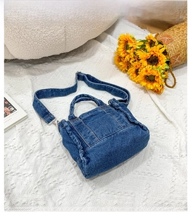 Detailed close-up of blue denim small crossbody bag with adjustable straps on lace background