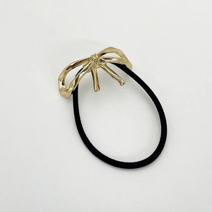Nahaufnahme von schwarzem Haargummi mit eleganter goldener Metall Schleife Deko