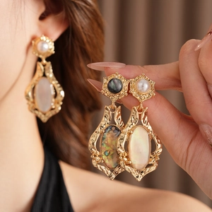 Gros plan de boucles d'oreilles baroques dorées avec nacre sur l'oreille du mannequin