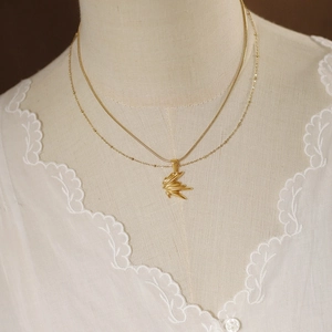 Close-up of golden double-layer necklace with maple leaf pendant on white lace background