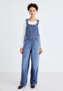 Front full shot of stylish blue denim overalls paired with a clean white long sleeve shirt