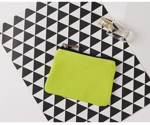 Detailed top view of grass green canvas coin purse with silver zipper on geometric background