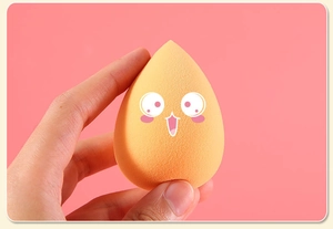 Close-up of an orange makeup sponge featuring a cute smiley face on a pink background