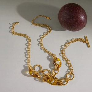 Goldene Gliederkette mit bernsteinfarbenen Harzringen und Strass auf neutralem Grund