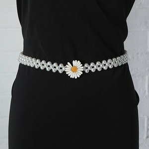 Detail of elegant pearl waist chain featuring a white daisy flower buckle on a black dress