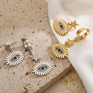 Gold and silver star devil eye clip earrings with blue stones on white silk background
