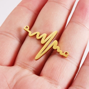 Golden stainless steel heartbeat charm connector held in hand for jewelry making