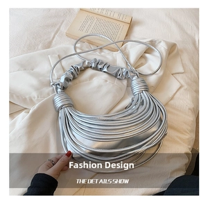 Detailed view of silver pleated handbag with multi-layer strap design and smooth metallic finish
