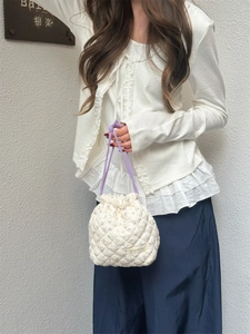 Detailed view of a white quilted floral drawstring pouch with purple rope straps