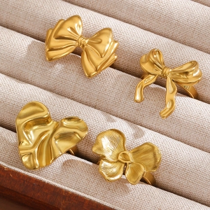 Detail of four vintage gold bow, heart and flower rings in a beige velvet jewelry box