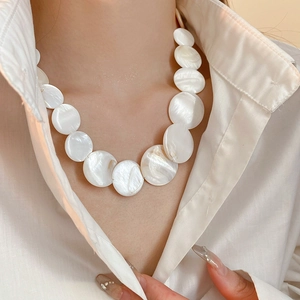 Detail of a white shell necklace for women on model wearing a white collar shirt