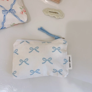 Detail of white cotton pouch featuring blue bow patterns and simple wish woven label