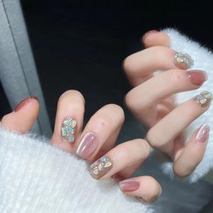 Faux ongles œil de chat rose avec paillettes scintillantes et strass sur main de mannequin