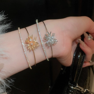 Close-up of stacked gold and silver firework starburst bracelets with zircon stones