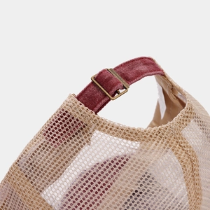 Detailed close-up of mesh fabric with velvet strap and bronze buckle on baseball cap