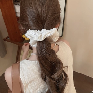 Vue détaillée d'un chouchou en dentelle blanche avec étiquette et texture florale élégante