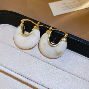 Gros plan détaillé de boucles d'oreilles vintage en U en résine avec métal doré et marbre