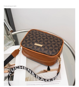 Detail of trendy brown crossbody camera bag with dual zipper layers and wide strap